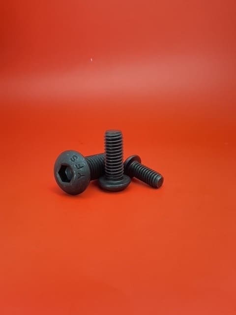 A black plastic screw and nut on top of an orange background.