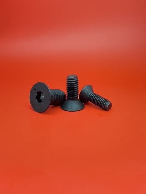 A group of three black screws sitting on top of a red table.