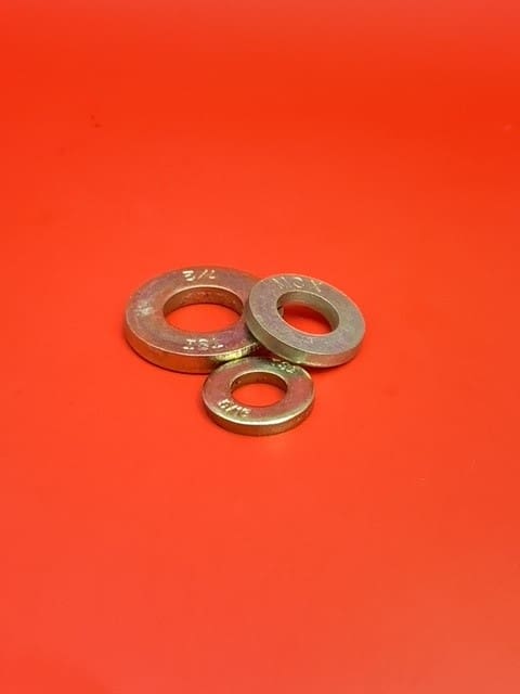 A group of three metal washers on top of a red surface.