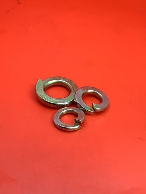 A group of three metal washers on top of a red surface.