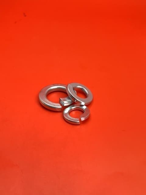 A group of three metal washers on top of a red surface.