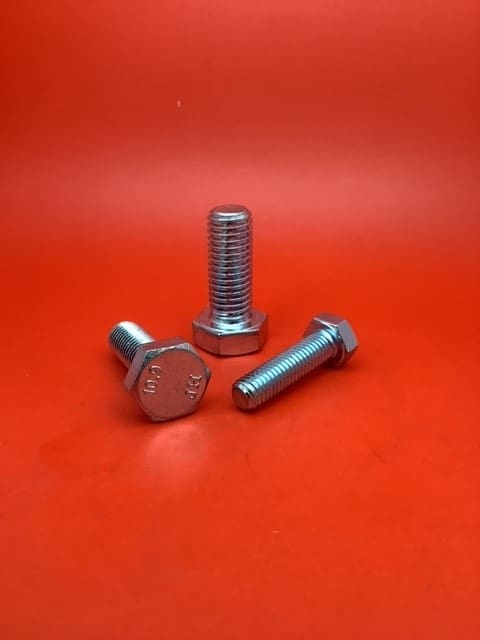 A group of three bolts sitting on top of a red table.