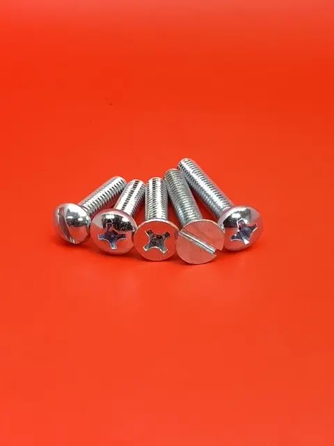 A group of four screws sitting on top of a red surface.