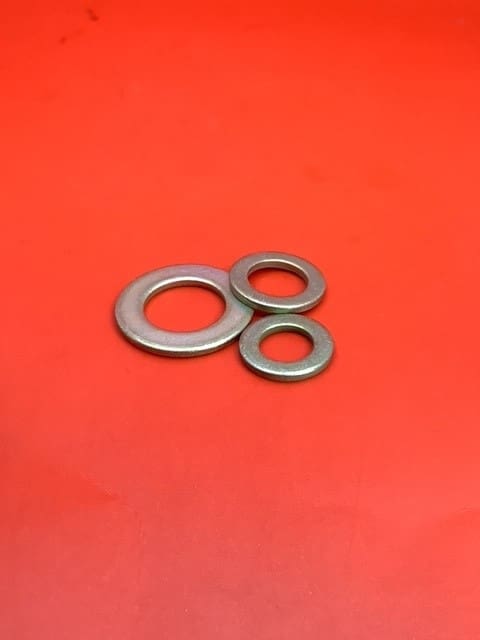 A group of three metal washers on top of a red surface.