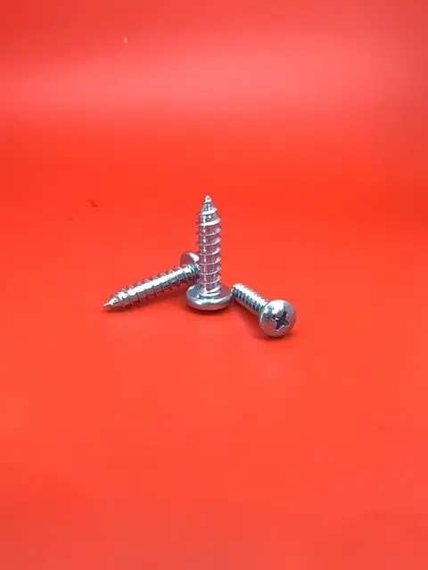 A close up of some metal screws on a red surface