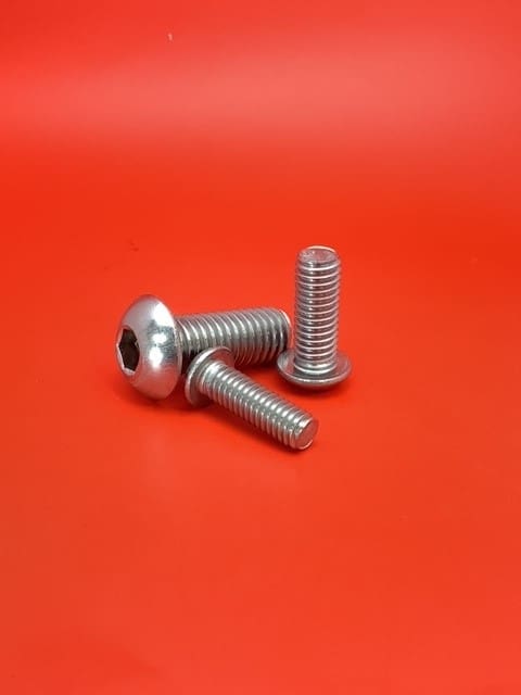 A pair of stainless steel bolts sitting on top of a red table.