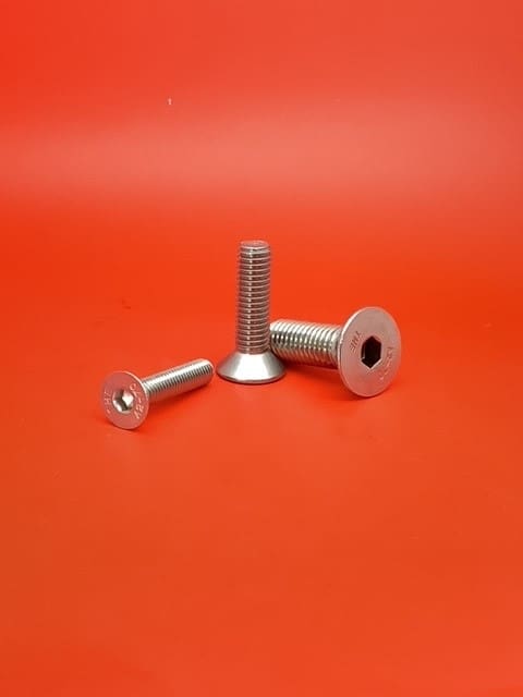 A group of three metal bolts on top of a red surface.