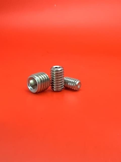 A group of three metal screws sitting on top of a red table.