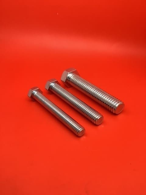 A group of three bolts sitting on top of a red table.