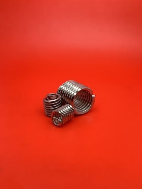 A group of three different sized metal threaded inserts.