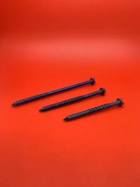 A group of three nails on top of a red surface.