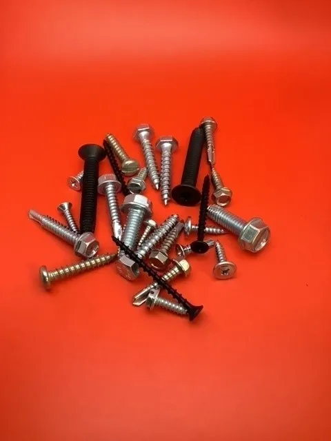 A pile of nuts and bolts on top of a red surface.