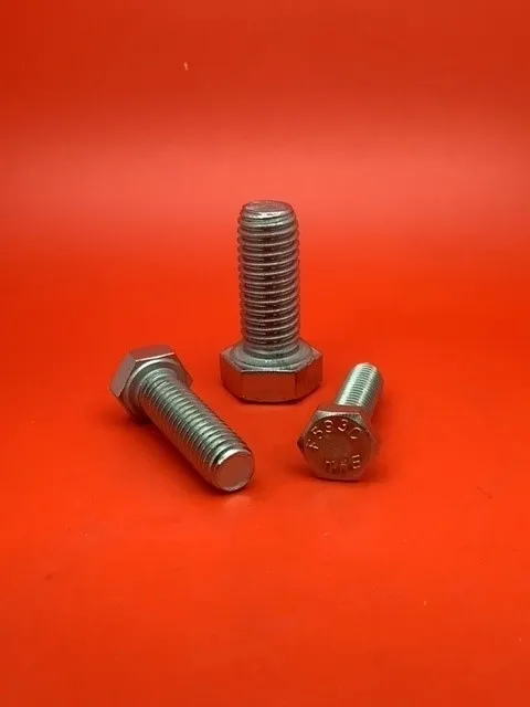 A group of three nuts and bolts on top of a red surface.