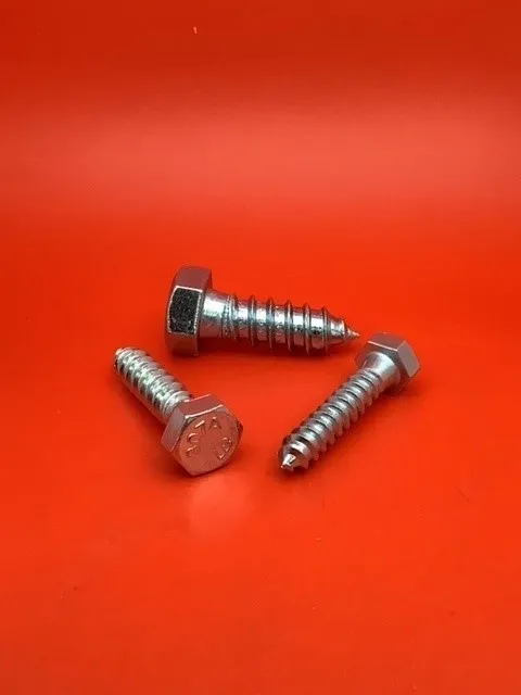 A group of three bolts and nuts on top of a red surface.