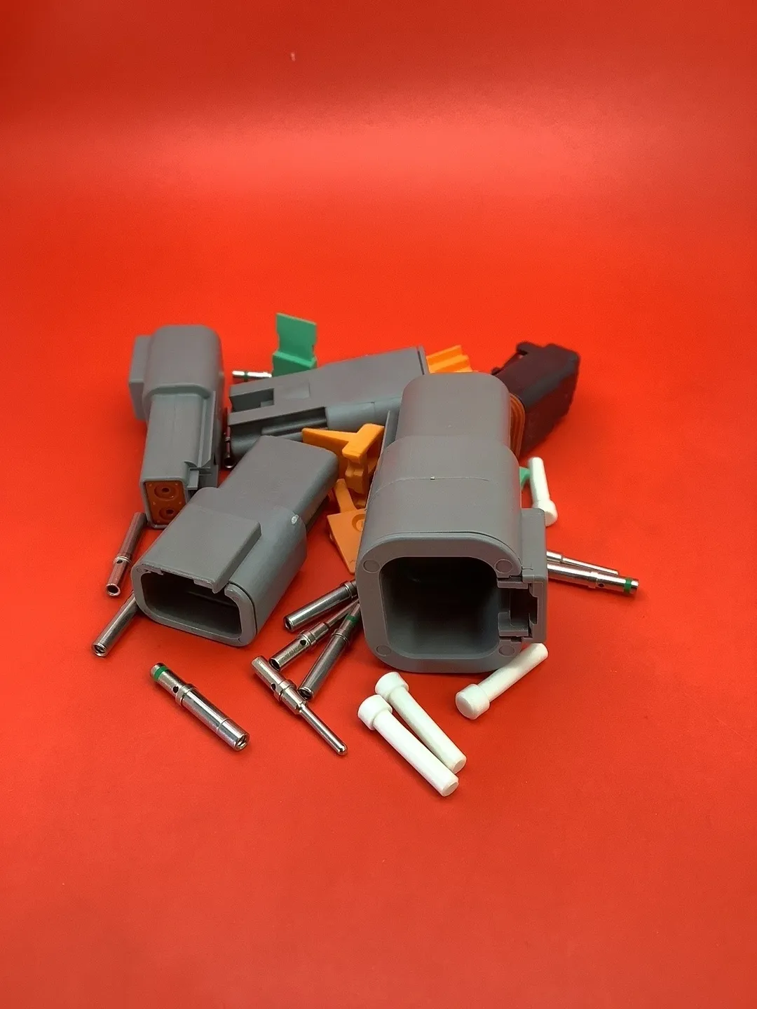 A pile of electrical connectors and pins on top of a red surface.