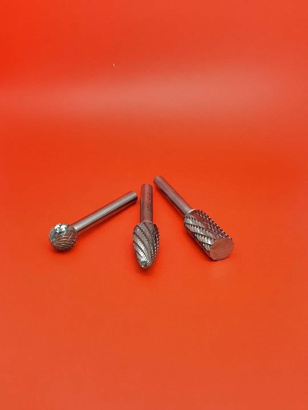 A set of three drill bits on top of an orange background.