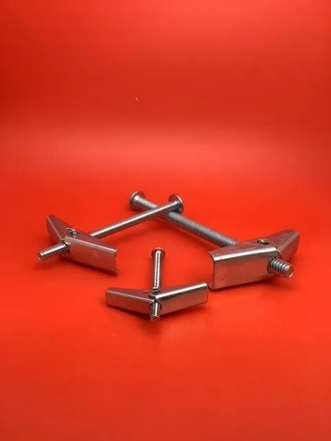 A group of four metal nails on top of a red surface.